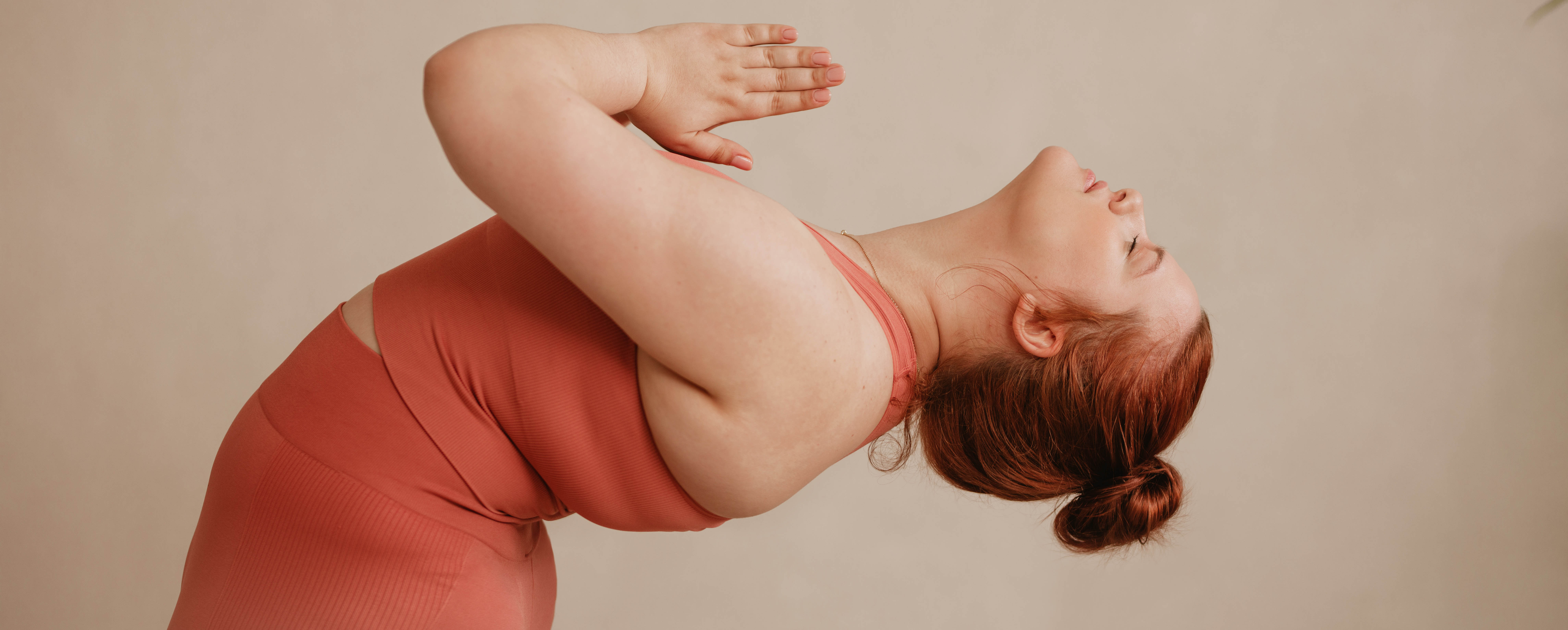 Woman doing a standing yoga backbend in an orange workout oufit Woman doing a standing yoga backbend in an orange workout oufit